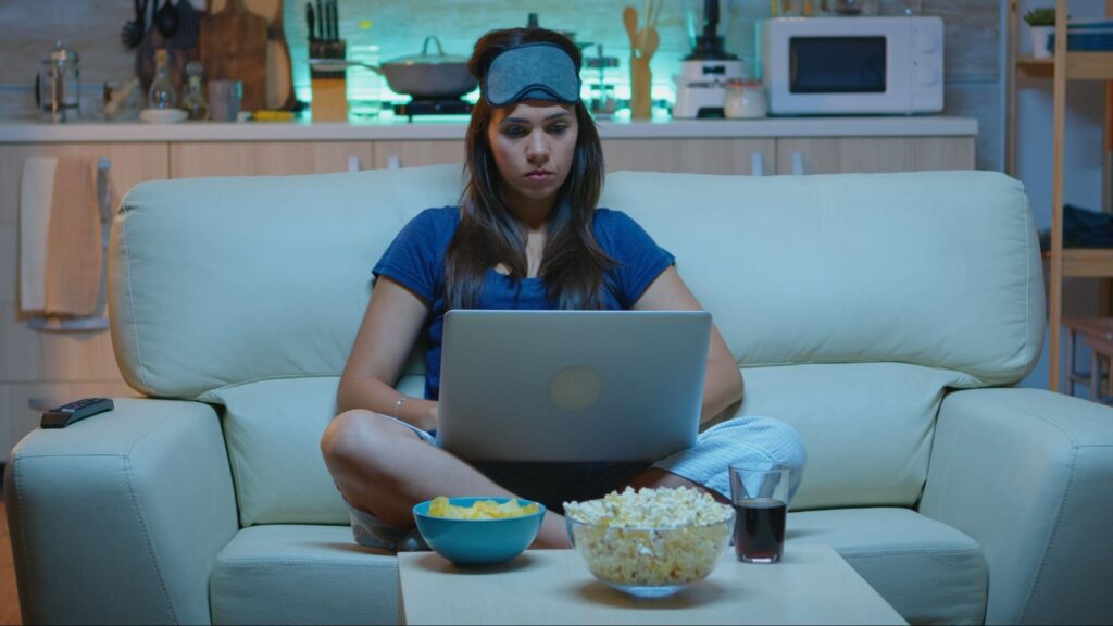 Woman in pajamas using a laptop on the couch at night